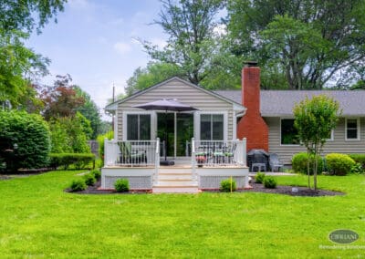 Rear elevation of home addition with centered deck, sliding glass doors, and balanced exterior design