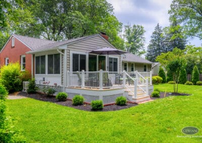 Angled view of home addition with wraparound deck, white railing, and expanded living space