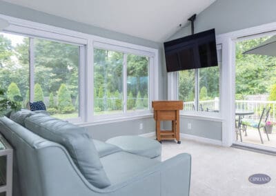 Sunroom addition with large windows, seating area, and deck access