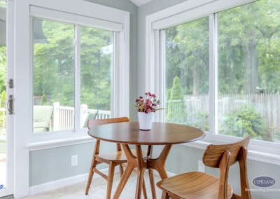 Sunroom dining nook with round table, chairs, and wraparound windows