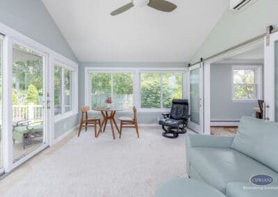 Sunroom connected to interior living space A bright sunroom featuring a dining nook and lounge seating, with sliding barn-style doors that create a flexible connection to the home’s interior living areas.