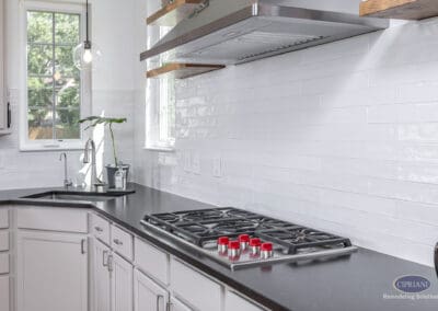 Modern cooktop and sink area with black countertops, white subway tile backsplash, and custom cabinetry in a Moorestown kitchen remodel.
