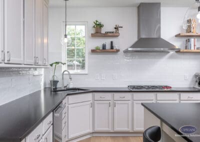 White kitchen workspace with black countertops, open wood shelving, and stainless steel range hood in a Mount Laurel kitchen remodel.