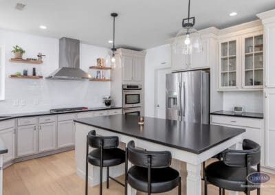 White kitchen with large black island, glass pendant lighting, and stainless steel appliances in a Mount Laurel kitchen remodel.