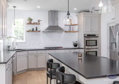 White kitchen with black island seating, stainless steel range hood, and floating wood shelves in a Mount Laurel kitchen remodel.
