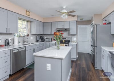 Gray Shaker Kitchen Layout with Island – A Sicklerville kitchen remodel featuring gray shaker cabinets, quartz countertops, a centered island, stainless steel appliances, and durable wood-look flooring.