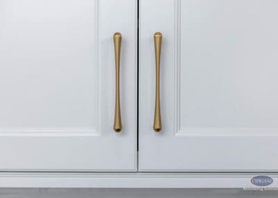 Warm Brass Cabinet Hardware Detail: Close-up of elongated brass pulls on white shaker-style kitchen cabinet doors highlighting refined modern design.