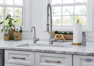 Kitchen Sink with Spring Pull-Down Faucet: Bright window-side kitchen sink featuring a spring pull-down faucet, marble countertop, and clean white tile backdrop.