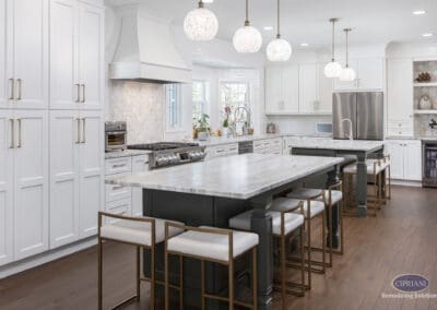 Timeless Gathering Kitchen with Double Islands: Bright Mount Laurel kitchen featuring dual marble islands, white shaker cabinetry, custom range hood, pendant lighting, and warm wood flooring designed for gathering and entertaining.