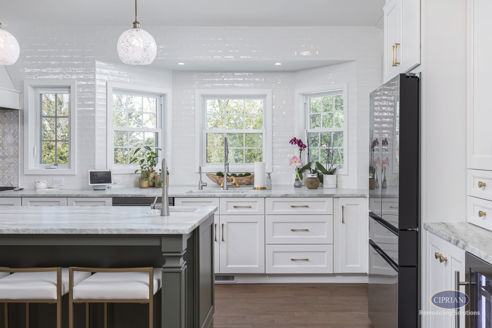 Timeless Gathering Mount Laurel Kitchen Remodel Window View | Cipriani Remodeling Solutions Timeless Gathering Mount Laurel Kitchen Remodel: Bright white kitchen with triple windows, marble countertops, custom cabinetry, and layered island seating designed for functional everyday living.