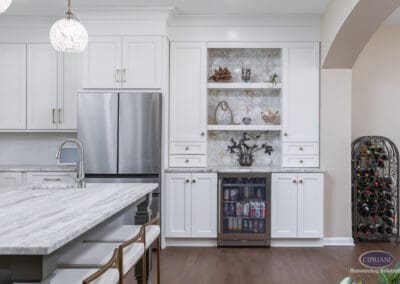 Timeless Gathering Mount Laurel Kitchen Remodel: Custom beverage center with open shelving, patterned tile backdrop, marble countertop, and integrated beverage refrigerator alongside layered island seating.
