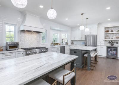 Timeless Gathering Mount Laurel Kitchen Remodel: Dual marble islands, custom white cabinetry, statement range hood, and decorative backsplash creating a bright and elegant cooking and entertaining space.