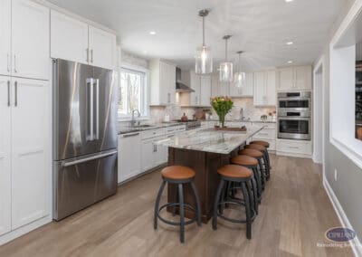 Open kitchen with expansive island seating and glass pendant lighting. Light cabinetry and warm wood accents create a balanced, inviting cooking space.