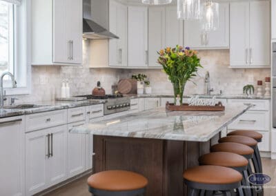 Stone kitchen island with waterfall-style edge and seating. Light cabinetry and soft neutral finishes create a calm, functional cooking environment.