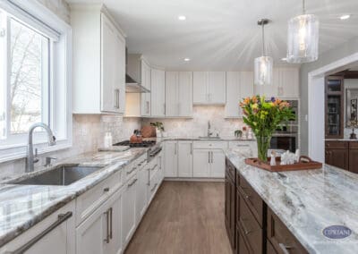 Bright transitional kitchen with white perimeter cabinetry, contrasting wood island, and natural stone countertops creating a calm, functional layout.