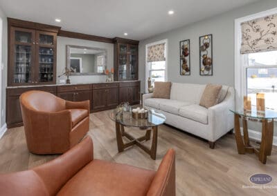 Comfortable lounge seating with custom built-in cabinetry backdrop. Warm leather chairs and neutral sofa create a welcoming gathering space with integrated storage.