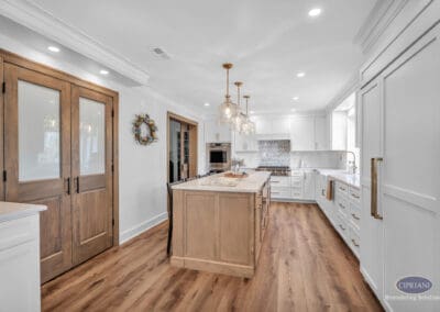 Kitchen with wood island, white cabinetry, glass pendant lighting, and sliding barn doors