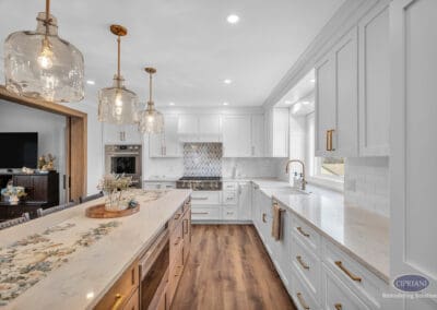 Kitchen island with quartz countertop, pendant lighting, and white cabinetry with brass hardware