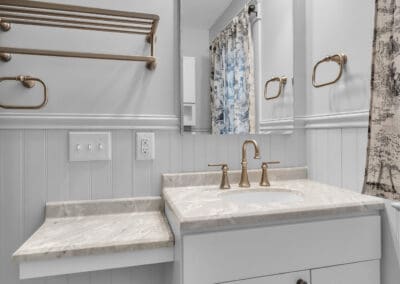 Bathroom vanity with integrated countertop, undermount sink, brass faucet, and side ledge