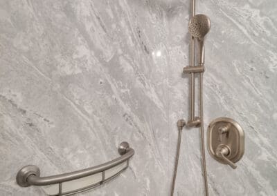 Shower wall with stone-look panels, grab bar, and dual shower head system