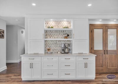 Built-in coffee bar with open shelving, decorative tile backsplash, and white cabinetry