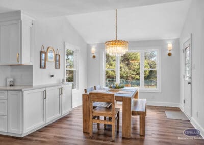 Dining area with wood table, white cabinetry, chandelier, and large windows