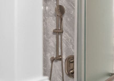 Shower system with rain shower head and handheld sprayer behind glass door