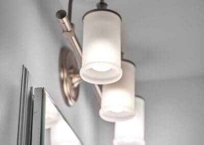 Bathroom vanity light with three frosted glass shades and warm metallic fixture