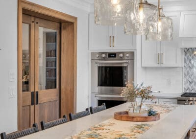 Kitchen island with seating, wood cabinetry, quartz countertop, and glass pendant lights