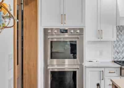 Built-in double wall ovens with white cabinetry and brass hardware