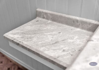 Light stone bathroom countertop detail with subtle veining and integrated backsplash