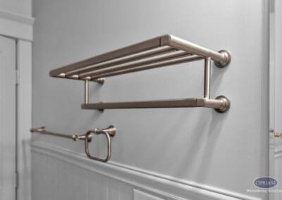 Wall-mounted towel shelf and bar in warm metallic finish above beadboard wainscoting