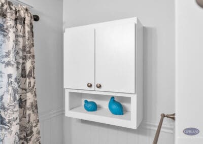 Wall-mounted white bathroom cabinet with open shelf and decorative accents