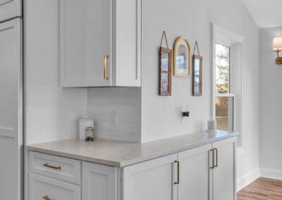 Kitchen cabinetry with quartz countertop, brass hardware, and side prep area