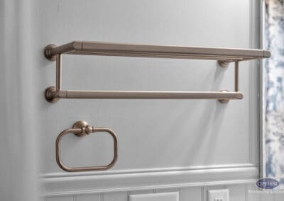 Wall-mounted towel shelf and ring in warm metallic finish on painted wall