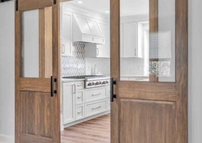 Open sliding barn doors with glass panels leading into kitchen