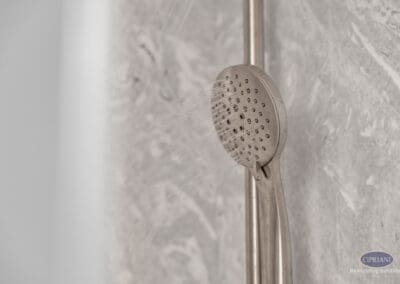 Handheld shower head with spray detail on sliding bar against stone-look wall