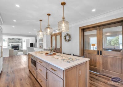 Wide view of kitchen with large island, pendant lighting, and sliding wood doors