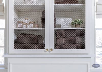 Linen cabinet with decorative wire mesh doors and folded towels in Mullica Hill bathroom